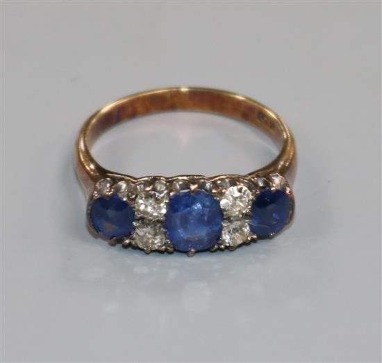 An early 20th century 18ct gold, three stone sapphire and four stone diamond ring, size M.